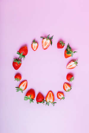 round frame made of fresh tasty strawberries on a lilac background. Beautiful background or greeting card. copy space, flat lay, border, vertical.の写真素材