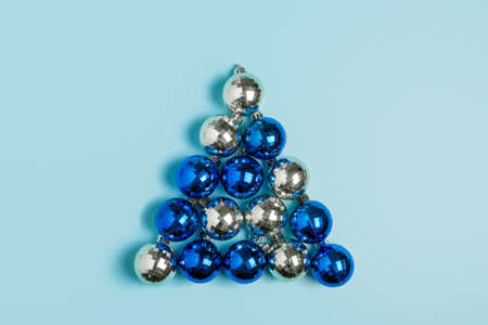 Christmas tree made of blue and silver christmas balls on a blue background. Christmas or New Year celebration concept. Minimalism, top view, flat lay, card.の写真素材