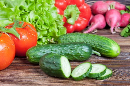 Fresh organic cucumber with slices on vegetables backgroundの写真素材