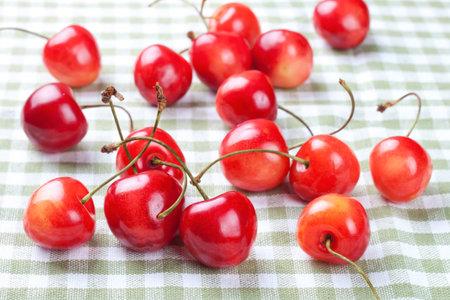 Scattered delicious ripe cherries on on plaid fabric background