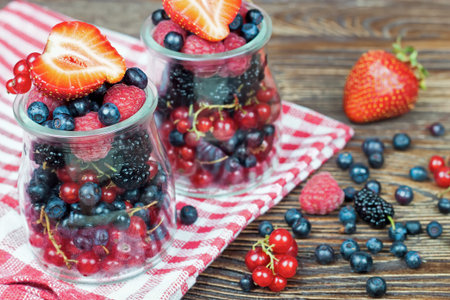 mixed berries in a in a glass jar on brown wooden backgroundの写真素材