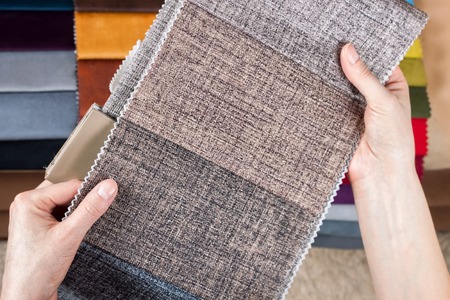 Woman chooses samples of colored fabric on table close upの写真素材