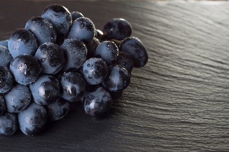 fresh ripe black grapes on dark slate background, top view.の写真素材