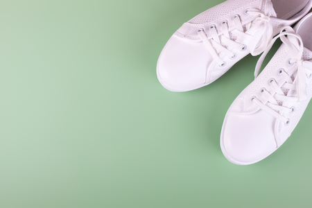 white female sneakers on green background with copy space. top view, flat lay.の写真素材