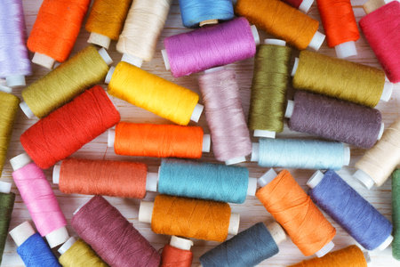 Multicolor sewing threads on white wooden background