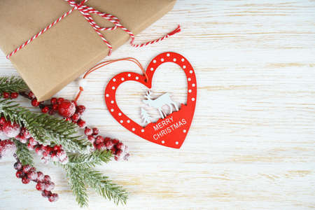 New year background with christmas tree branch, decorative heart with a deer and gift box on white wooden background with space for text. Flat lay, top view.の写真素材