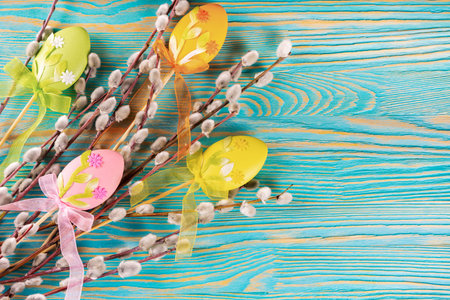 Willow tree branch with colorful eggs easter decoration on blue wooden backgroundの写真素材