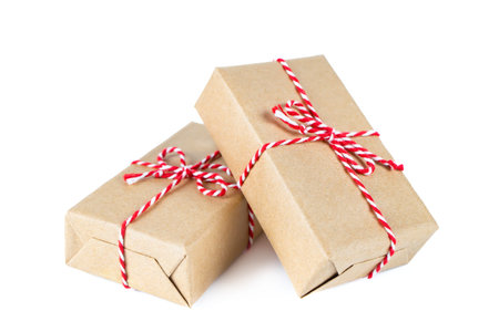 Two Christmas and New Year gift boxes wrapped in craft paper with red ribbon bow isolated on white...