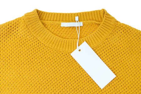 White blank rectangular clothing tag, label mockup template on yellow knitted sweater isolated on...