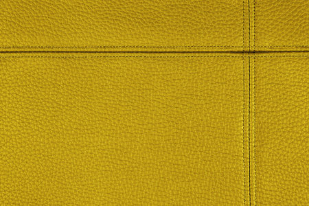 Natural, artificial yellow golden leather texture background with decorative seam. Material for sport items, clothing, furnitre and interior design. environmentally friendly leatherette.の写真素材
