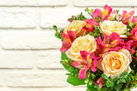 Bouquet of beautiful roses and alstroemeria on white brick background. Fresh, lush bouquet of colorful flowers for wedding, valenitnes day, mother day. Floral shop concept, mockup with copy spaceの写真素材