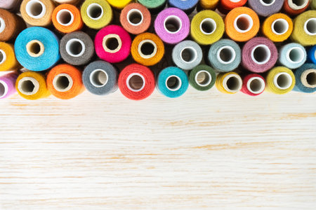 Sewing thread spools multicolored background, scattering of various colors sewing threads, colored yarns on white wooden surface with copy space. Flat lay, top view, mockup, templateの写真素材
