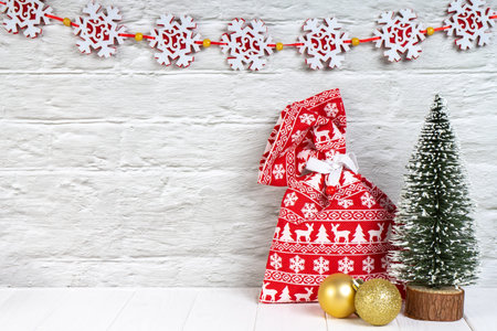 Decorative Christmas tree, red gift bag and golden balls on white wooden background with garland. Top view, flat lay with copy space, banner, header, New Year backgroundの写真素材