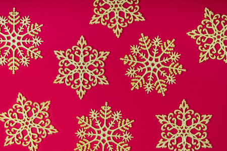 Golden glitter decorative snowlakes on red background. Christmas and New Year holiday wallpaper. Top view, flat lay, copy space, banner, hearder, mockup, backdropの写真素材