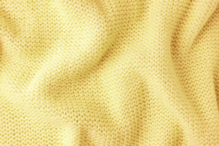 Close up background of knitted wool fabric made of viscose yarn. Bright yellow color crumpled...