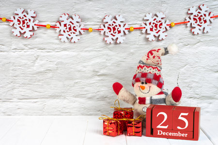Decorative Christmas snowman, gift boxes and red wooden perpetual calendar of cube with date on...