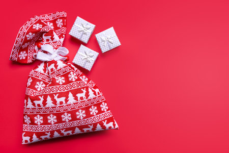 Decorative Christmas gift boxes and red gift bag with Christmas pattern on red background. Flat lay, top view, banner, header, mockup with copy space. Template for greeting cardsの写真素材