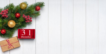 Christmas tree branch with decor, gift box and red perpetual calendar with date 31 december on white...