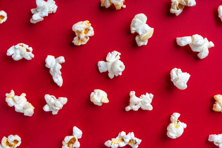 Scattered tasty cheese popcorn isolated on red background. Top view, flat lay, banner, wallpaper