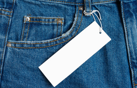 Front side pocket and price tag of blue jeans pants close-up. Denim background, texture, mockup....
