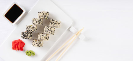 Sushi roll California with salmon, sesame seeds, avocado, cream cheese on white background. Rolls served on white dish with wasabi, ginger and soy sauce. Japanese cuisine food. top view, copy spaceの写真素材