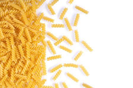 Fusilli spaghetti pattern, food background. Scattered raw pasta isolated on white background, ingredient for cook, traditonal italian cuisine. Banner, header, backdrop for restaurant menuの写真素材