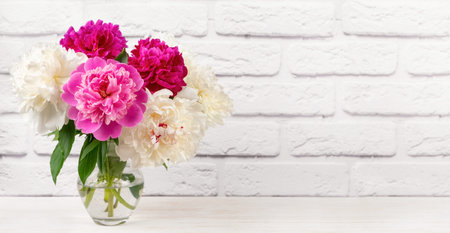 Bouquet of pink and white peony flowers in vase on white brick wall background. Mockup, template for holiday, birthday, mother's day. Banner, header with copy spaceの写真素材
