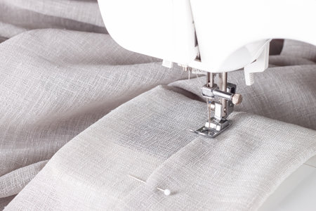 Modern sewing machine presser foot with linen fabric and thread, closeup. Sewing process clothes, curtains, upholstery. Business, hobby, handmade, zero waste, recycling, repair conceptの写真素材