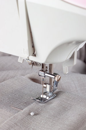 Modern sewing machine presser foot with linen fabric and thread, closeup. Sewing process clothes, curtains, upholstery. Business, hobby, handmade, zero waste, recycling, repair conceptの写真素材