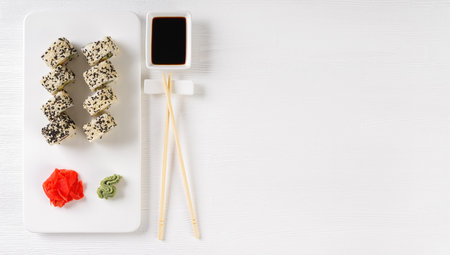 Sushi roll California with salmon, sesame seeds, avocado, cream cheese on white background. Rolls served on white dish with wasabi, ginger and soy sauce. Japanese cuisine food. top view, copy spaceの写真素材