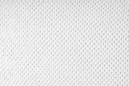 Close up background of knitted wool fabric with dots pattern. White color wool knitwear texture. Openwork abstract knitted jersey. Fabric abstract backdropの写真素材