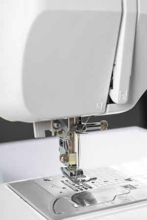 Modern white sewing machine presser foot closeup, macro. Sewing equipment, work tool for atelier...