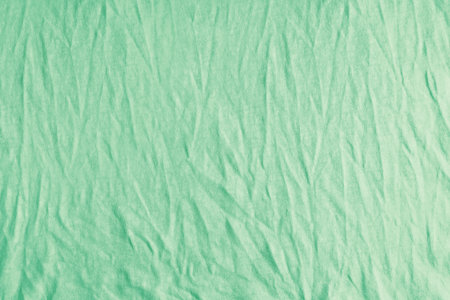 Wrinkled, crumpled green fabric texture background. Wrinkled and creased abstract backdrop of cotton jersey textile, wallpaper with copy space, top view.の写真素材
