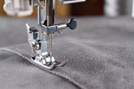 Modern sewing machine with gray velours fabric. Sewing process clothes, curtains upholstery....