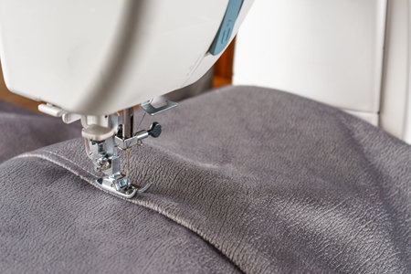 Modern sewing machine with gray velours fabric. Sewing process clothes, curtains upholstery....