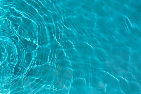 Transparent turquoise clear water surface texture with ripples, waves and rings in sunlight....