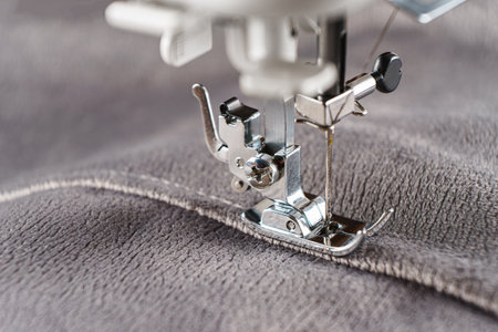 Modern sewing machine with gray velours fabric. Sewing process clothes, curtains upholstery. Business, hobby, handmade, zero waste, recycling, repair conceptの写真素材