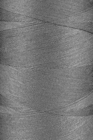 Texture of gray color threads in spool close up, macro. Sewing threads bobbin abstract background, wallpaper, backdrop.の写真素材