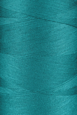Texture of turquoise color threads in spool close up, macro. Sewing threads bobbin abstract...