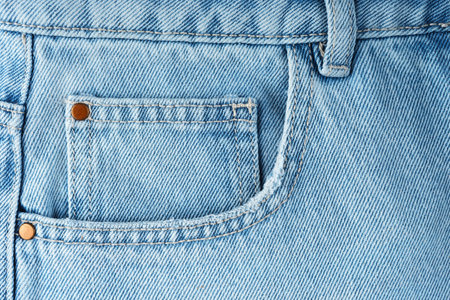 Front pocket and small pocket blue jeans pants close up, macro. Fashion concept, business, shopping, sale. Design detail, button and seams, copy spaceの写真素材