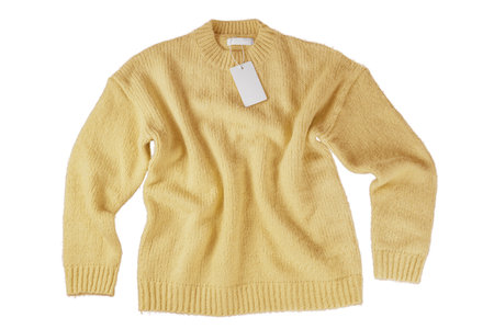 Yellow flying crumpled women's autumn knitted sweater with blank label tag isolated on white...
