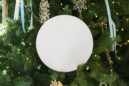 White blank circle paper on decorated Christmas tree branch background. Mockup, template, copy space...