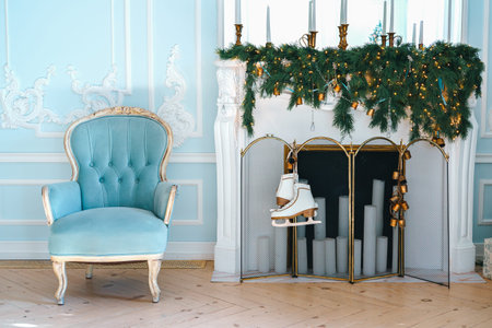 Christmas decorated living room features blue upholstered vintage chair, decorated fireplace with...