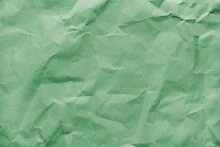 Recycled crumpled green colored paper texture. Wrinkled craft paper background, rough cardboard...