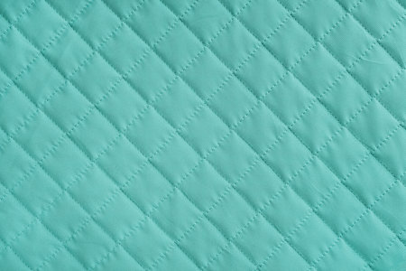 Checkered, diamond stitching pattern, turquoise quilted fabric background. Blanket or puffer jacket, stitch rhombus texture close up, macro. Wallpaper, backdrop.の写真素材