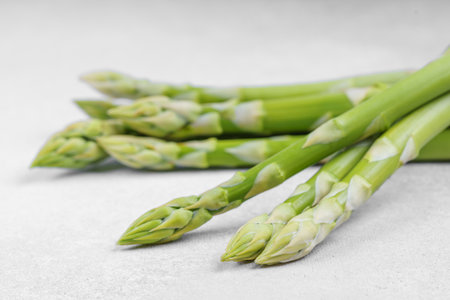 Bunch of raw fresh green asparagus stalks on light gray textured background. Healthy food, fresh produce, cooking ingredient, vegetarian recipe, or organic farming, agriculture.の写真素材