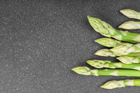 Bunch of raw fresh green asparagus stalks macro, close up on black textured background with copy space. Healthy food, fresh produce, cooking ingredient, vegetarian recipe, organic agriculture.の写真素材