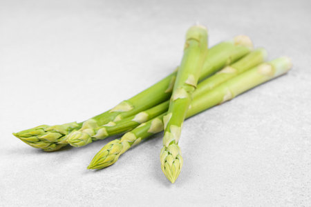 Bunch of raw fresh green asparagus stalks on light gray textured background. Healthy food, fresh produce, cooking ingredient, vegetarian recipe, or organic farming, agriculture.の写真素材