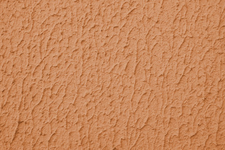 Close up of textured orange color painted wall with rough stucco, plaster wall texture. Vibrant...
