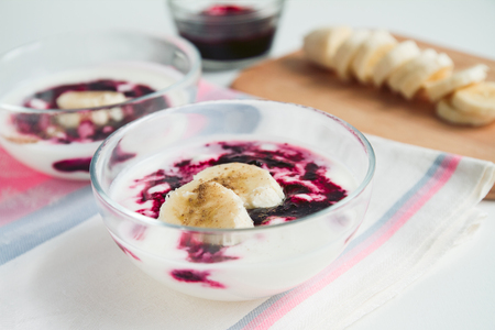 Organic yogurt with  bilberry jam and banana slices, sprinkled with cinnamon. Selective focus.の写真素材
